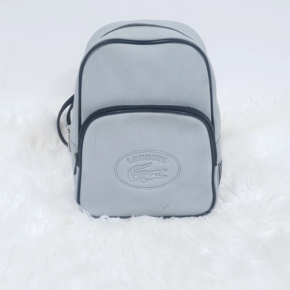 Lacoste mini backpack in a soft light blue shade with navy blue trim accents.